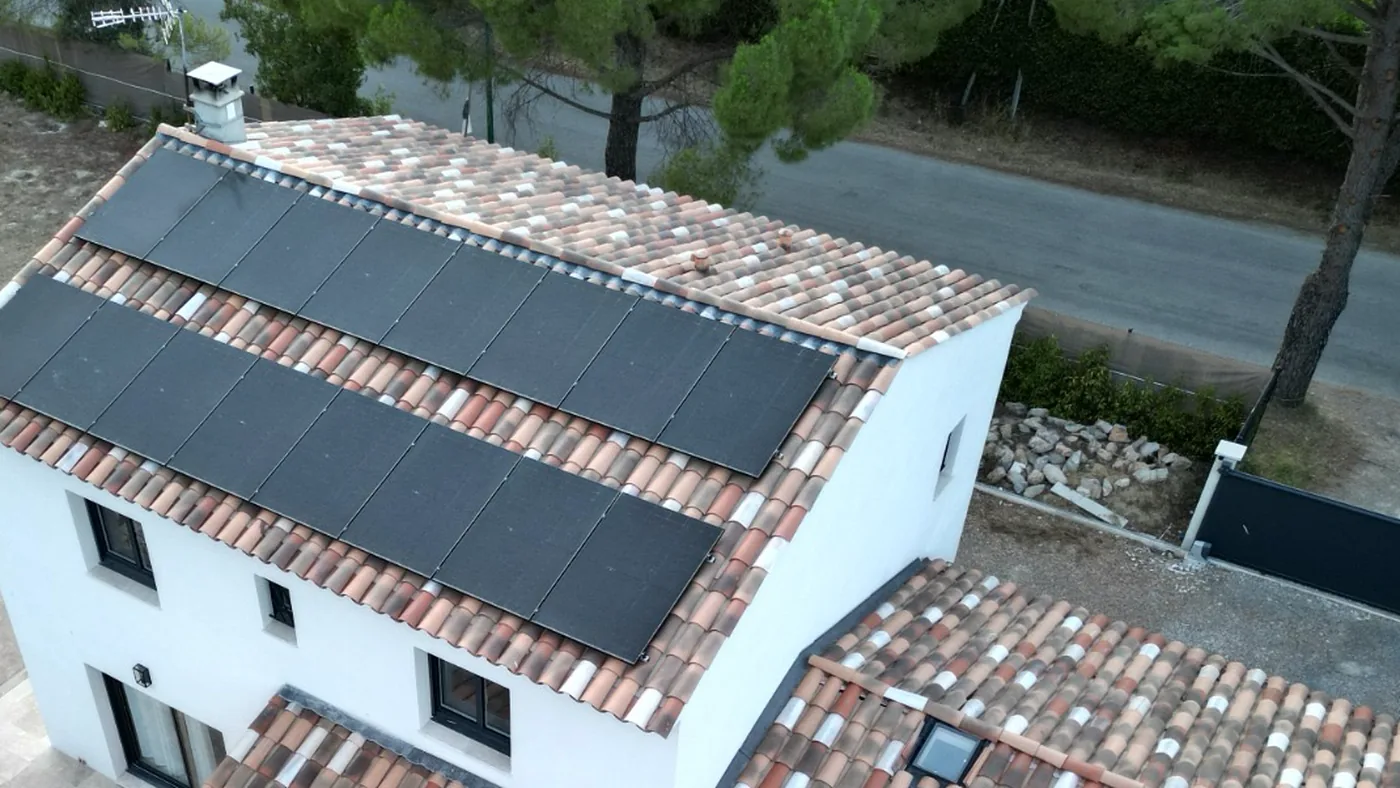 Vue aérienne de panneaux photovoltaïques posés sur le toit en tuiles d'une villa à étage, à Lorgues