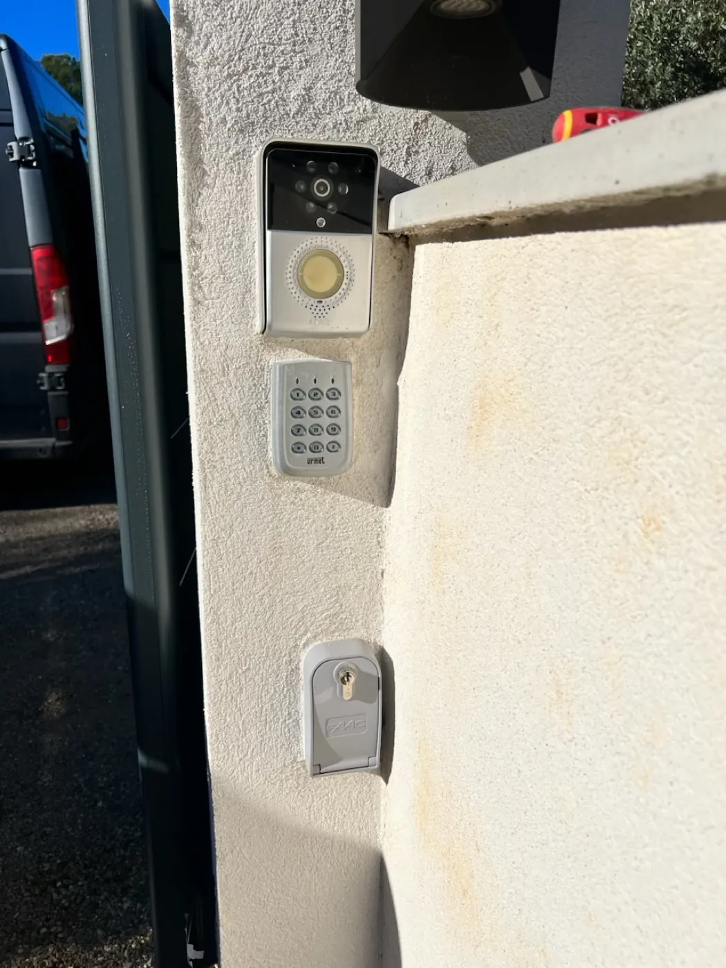 Pilier crépi avant intervention : platine, clavier à code Urmet et serrure à clé FAAC installés séparément.