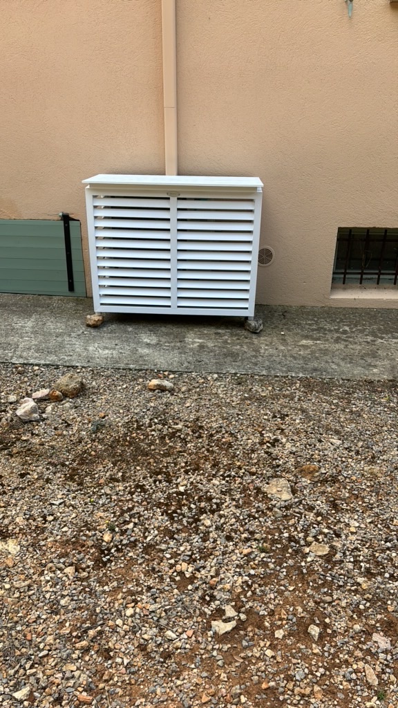 Habillage blanc à claire-voie autour d'une unité extérieure de climatisation