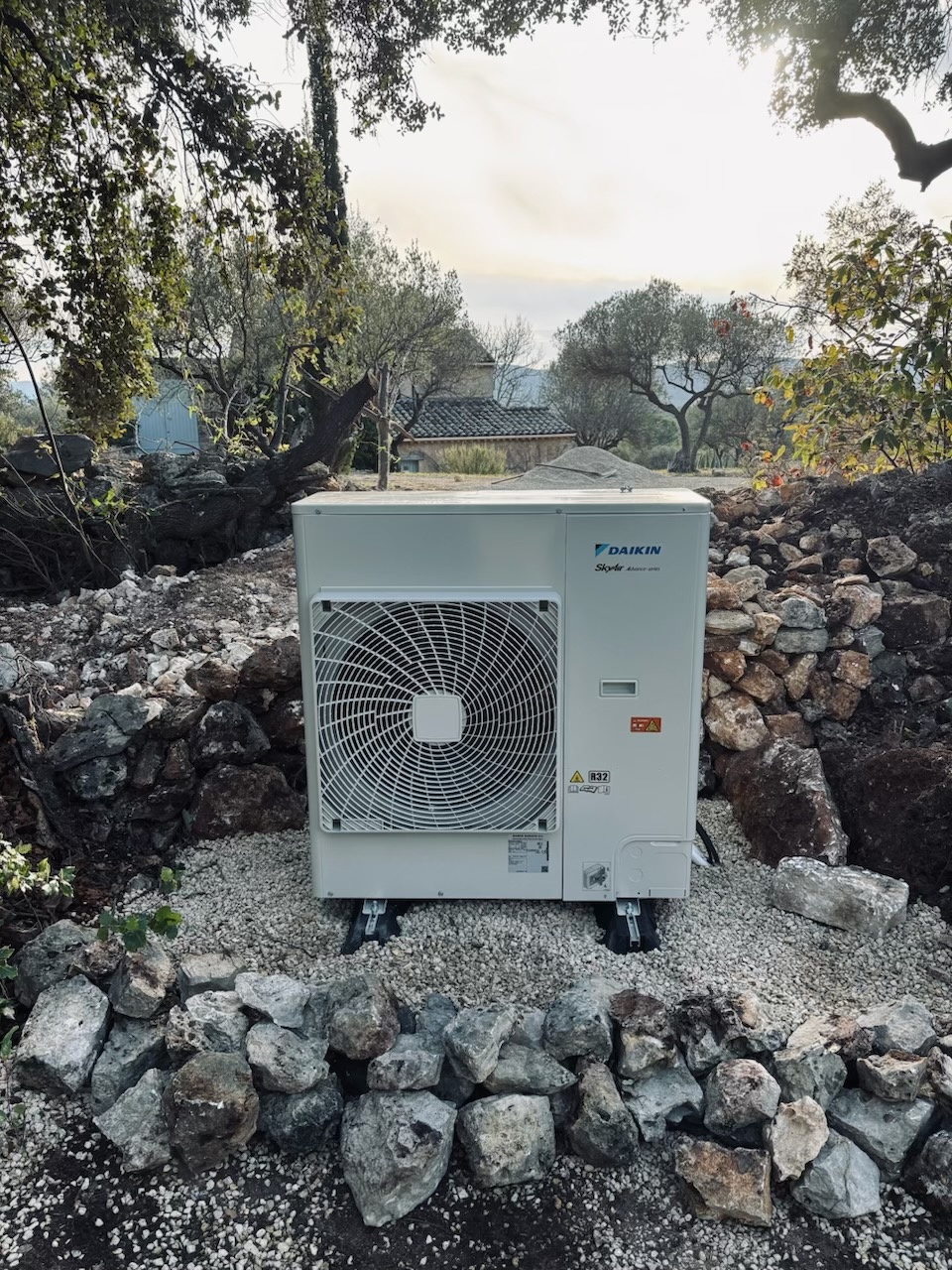 Groupe extérieur Daikin posé sur un lit de pierres